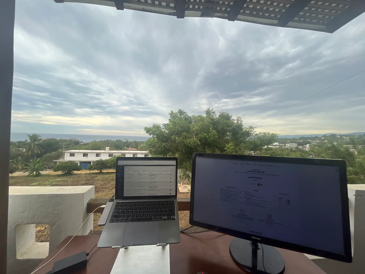 Patrick's balcony workspace in Mexico: a laptop and monitor with an ocean view behind them.